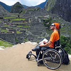 Der Autor Reinfried Blaha sitzt in seinem Rollstuhl auf einer Aussichtsterrasse in Machu Picchu und zeichnet die Reste der Stadt aus Inkazeiten nach.