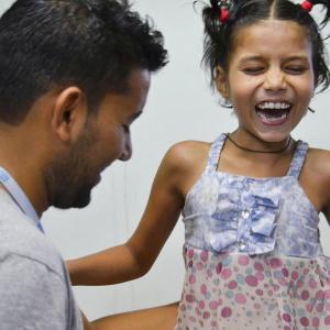 Die beinamputierte siebenjährige Nirmala lacht fröhlich im Gespräch mit einem jungen Arzt in Nepal.