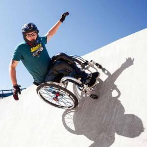 Ein junger Mann im Rollstuhl auf waghalsiger Fahrt in einer Skateboard-Anlage.