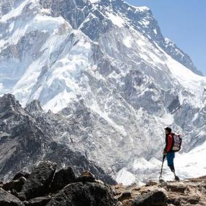 Ein Mann steht mit seinen zwei Beinprothesen an einem Bergrücken und sieht in Richtung eines schneebedeckten Gipfels. 