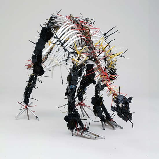 Skulptur eines Dinosauriers aus verschiedenen Materialien wie Kabel und Plastik in Schwarz, Weiß, Rot und Gelb. Die dynamische Haltung des Dinosaur...
